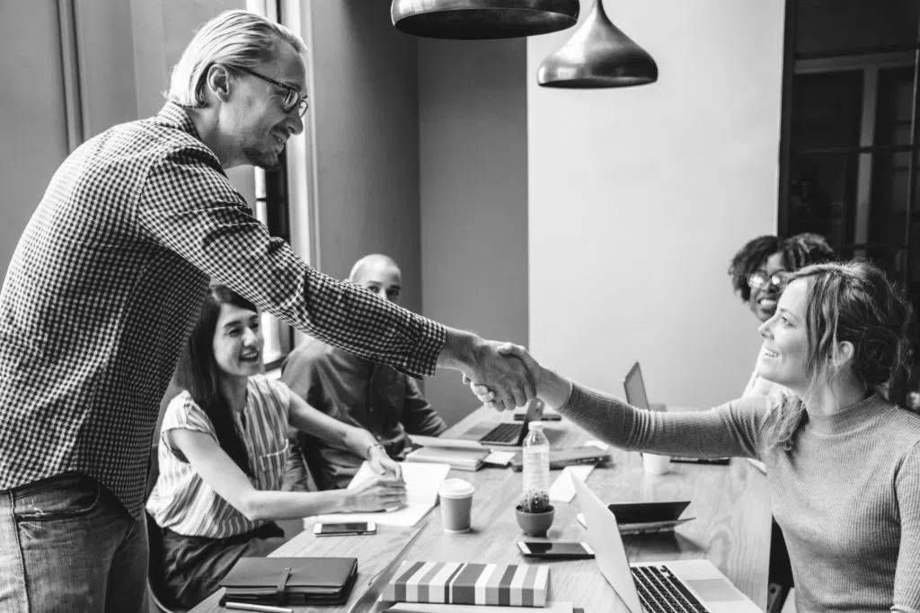 consultants in group working at desk shaking hands