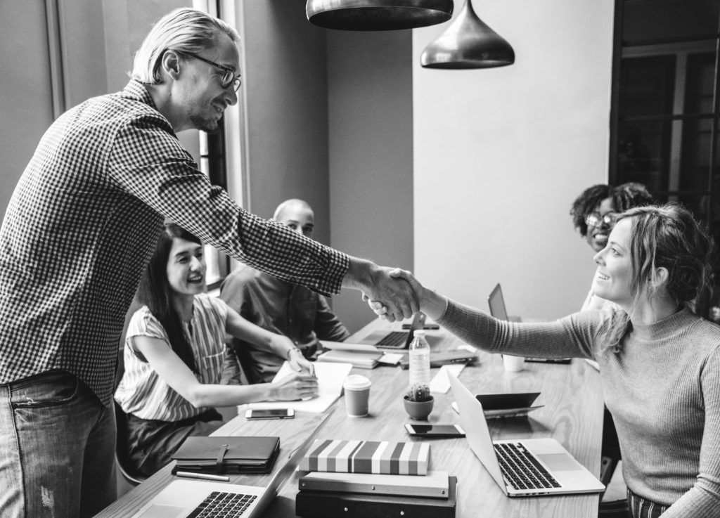 consultants in group working at desk shaking hands