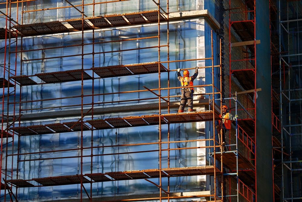 Construction workers installing scaffolding.